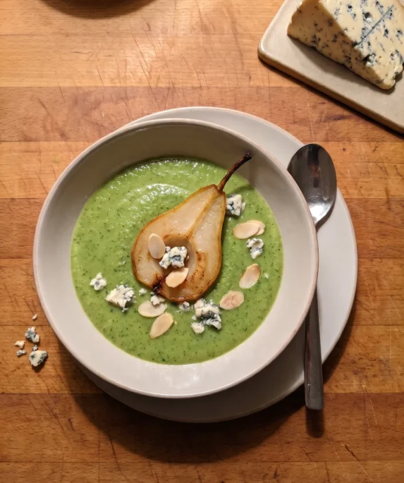 Gordon Ramsay broccoli and Stilton soup: bright green soup with a pan-roasted pear half, crumbled Stilton and toasted almonds in a bowl