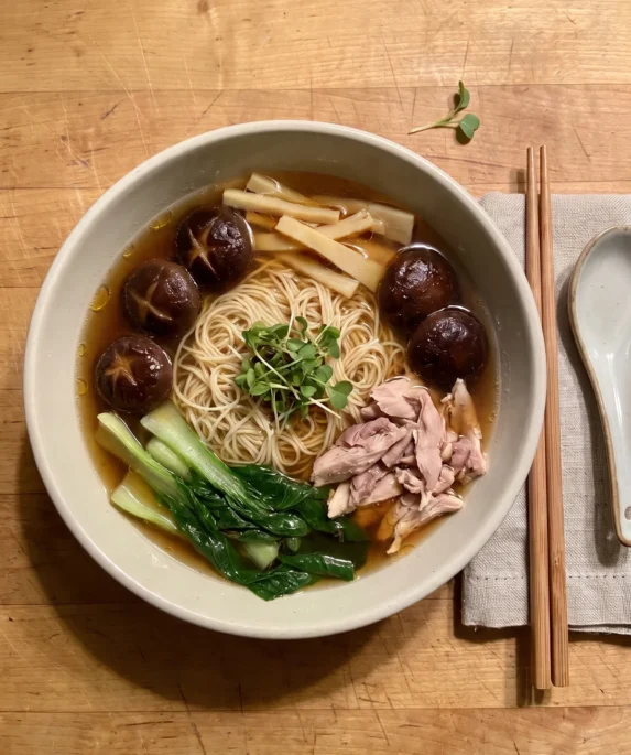 Gordon Ramsay chicken noodle soup: a bowl of egg noodles, shredded chicken, shiitake mushrooms, bamboo shoots and choi sum in a clear dark broth
