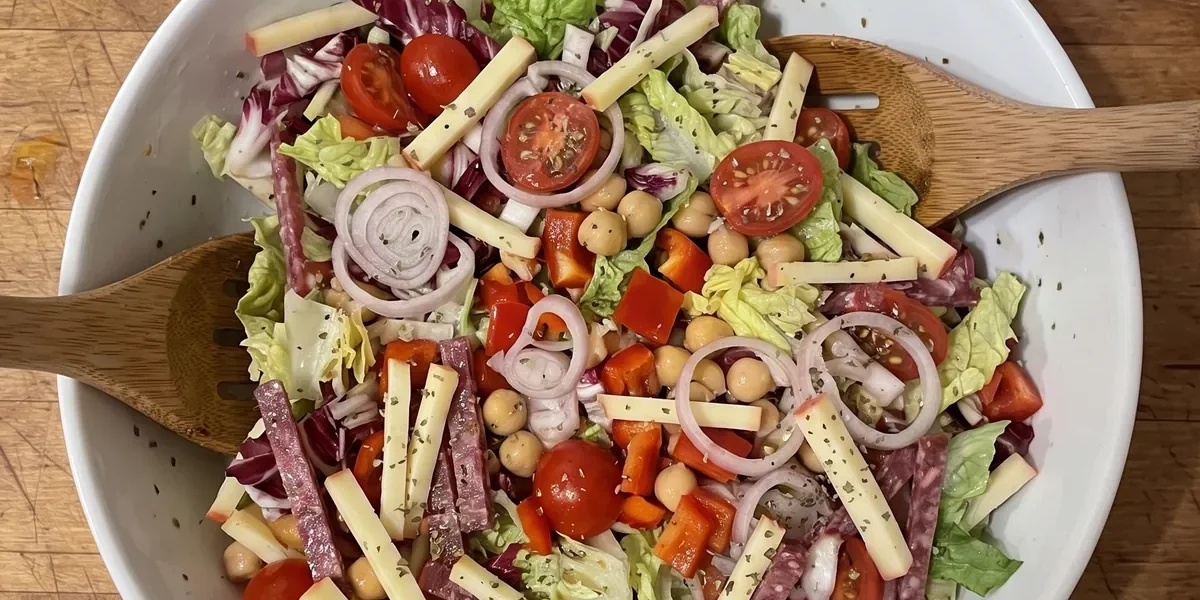 Gordon Ramsay chopped salad: shredded romaine and radicchio with cherry tomatoes, red pepper, chickpeas, Edam matchsticks and salami strips, dried oregano on top, in a big bowl