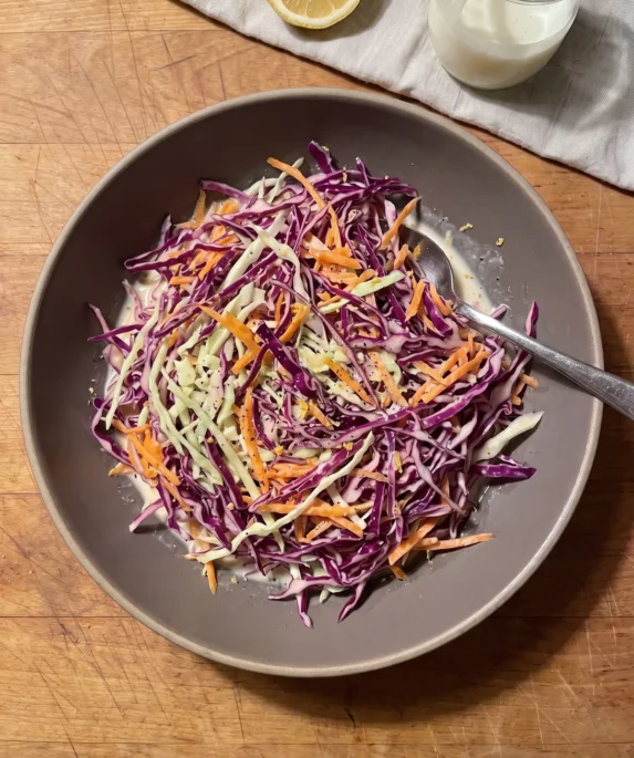 Gordon Ramsay buttermilk coleslaw: thin shreds of red and green cabbage with grated carrot in a light buttermilk dressing, in a stoneware bowl