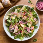 Gordon Ramsay ploughman's salad: romaine and watercress with apple, radishes, torn ham, Cheddar shavings, Stilton cubes and pink pickled red onion rings in a bowl