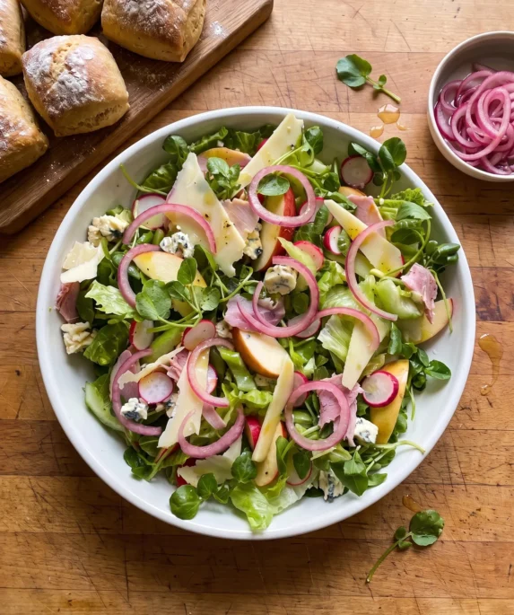 Gordon Ramsay ploughman's salad: romaine and watercress with apple, radishes, torn ham, Cheddar shavings, Stilton cubes and pink pickled red onion rings in a bowl