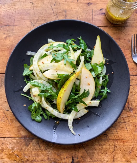 Gordon Ramsay rocket salad: wild arugula, watercress, thin curled fennel and long slices of Comice pear with a honey mustard vinaigrette