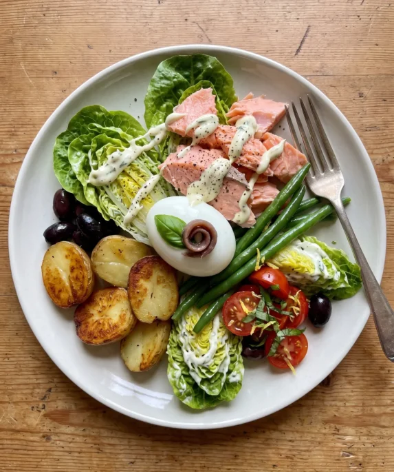 Gordon Ramsay salmon niçoise salad with poached salmon flakes, a coddled egg topped with basil and anchovy, golden potatoes, green beans and baby gem in tarragon mayonnaise