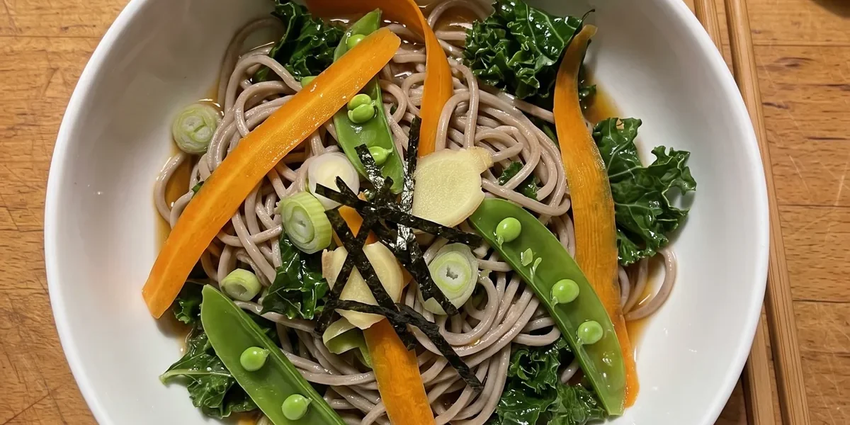 Gordon Ramsay soba noodle salad: brown buckwheat soba noodles with orange carrot ribbons, green sugar snap peas, dark kale, scallions and strips of nori in a white bowl