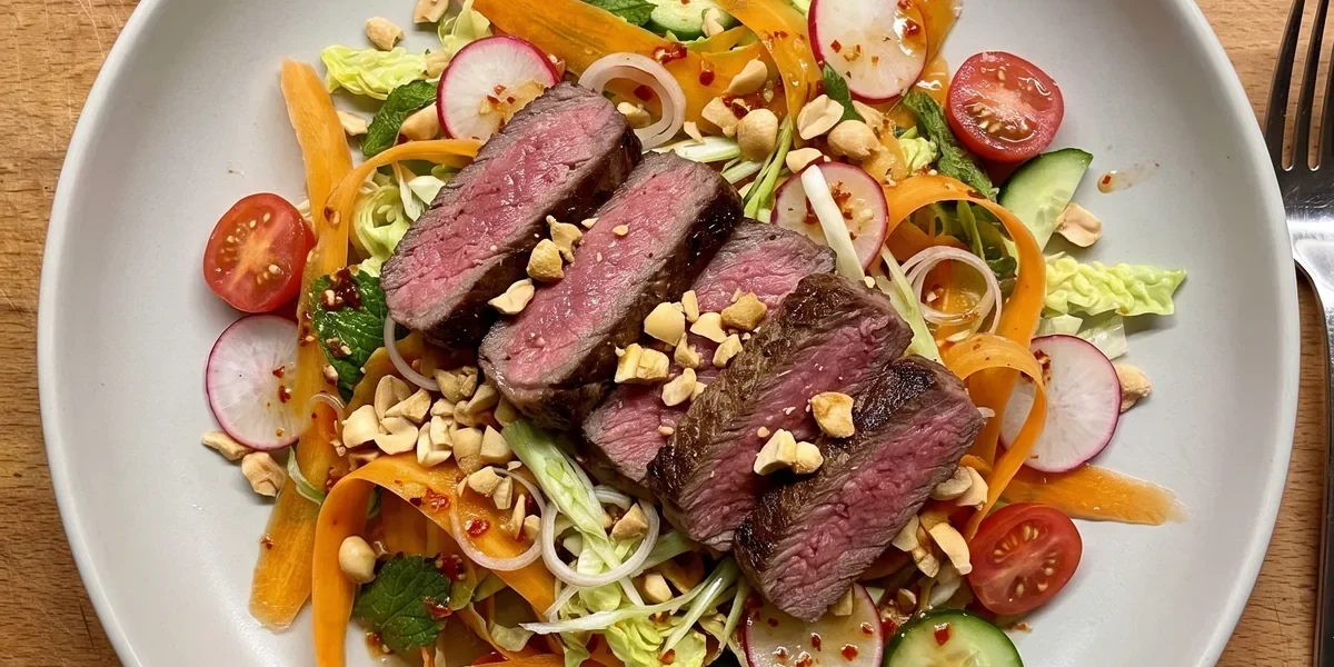 Gordon Ramsay spicy beef salad: thick slices of medium-rare sirloin steak over carrot ribbons, radishes, cherry tomatoes, cucumber, baby gem and mint with crushed peanuts