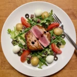 Gordon Ramsay seared tuna niçoise salad with pink tuna steak, quail's eggs, green beans, new potatoes, olives and tomatoes on baby leaves